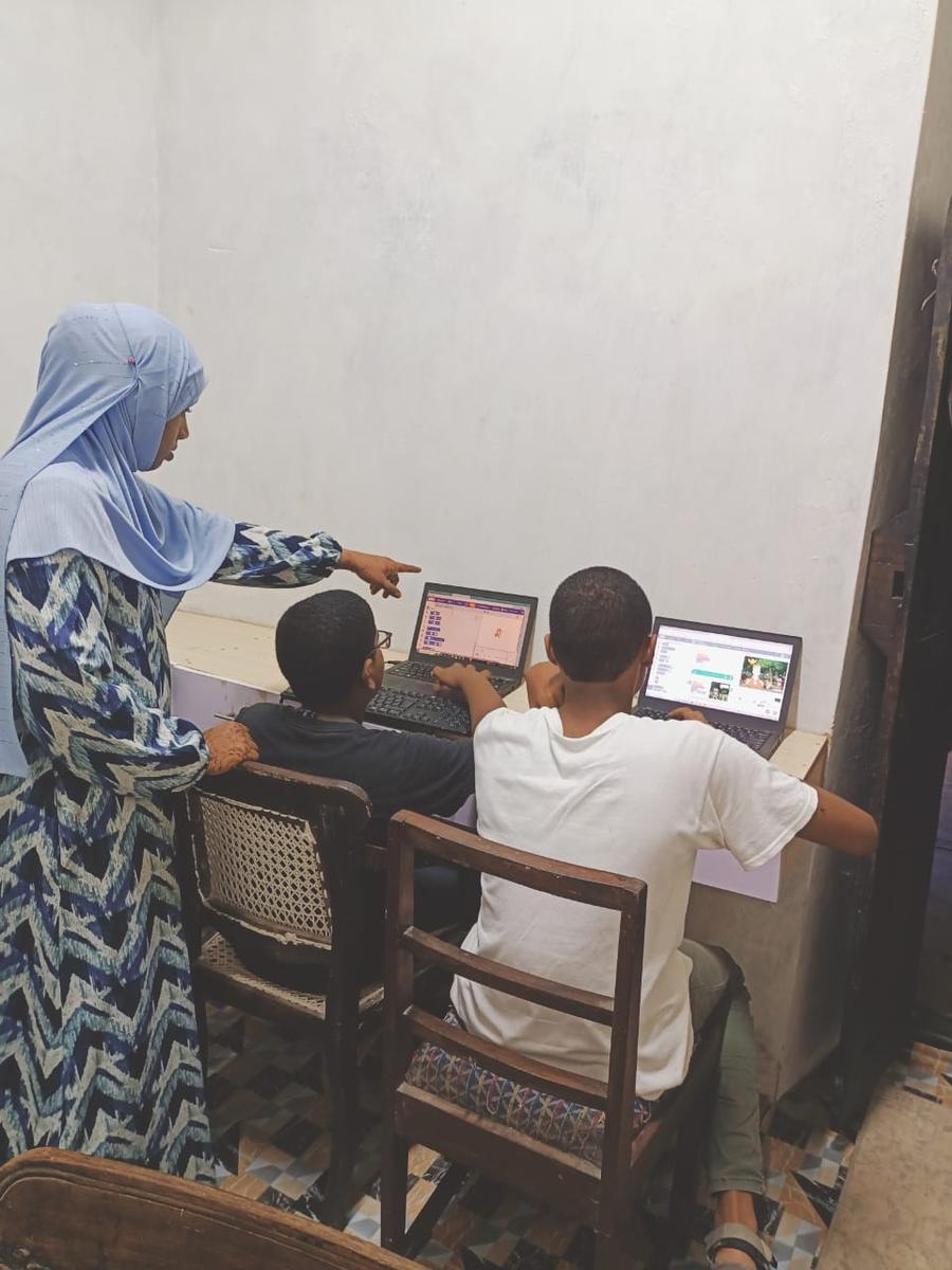 Mentor guiding students on laptops at Lamu Tech Hub