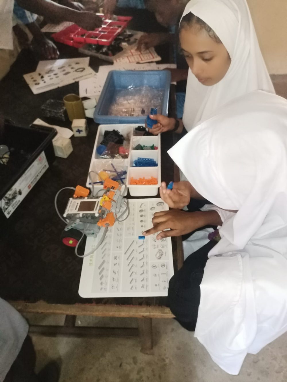 Two girls sorting robotics building blocks during a STEAM and AI bootcamp in Lamu